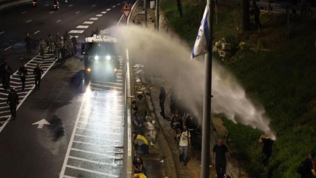 تستخدم الشرطة خراطيم المياه لتفريق أفراد عائلات وأنصار الرهائن الإسرائيليين الذين تحتجزهم حماس في غزة، خلال مسيرة احتجاجية أغلقت طريق أيالون السريع، في تل أبيب - 30 مارس/آذار 2024