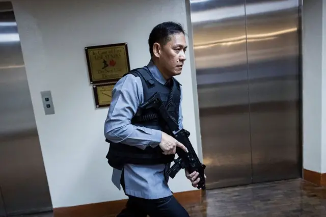 Seorang petugas keamanan Senat Filipina bereaksi setelah suara tembakan terdengar di gedung tersebut, pada Rabu (13/05). 