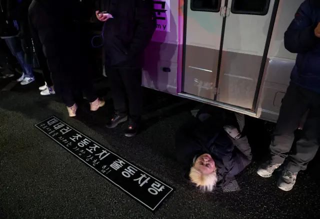 Una mujer se tumba en una carretera para bloquear un vehículo que transporta una unidad del ejército el 4 de diciembre de 2024, después de que el presidente de Corea del Sur, Yoon Suk-yeol, declarara la ley marcial.