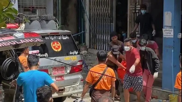 တိုက်ခန်းထဲ သေဆုံးသွားသူတွေရဲ့ ရုပ်အလောင်းတွေကို ပရဟိတအဖွဲ့တွေ သယ်ယူနေမှု 