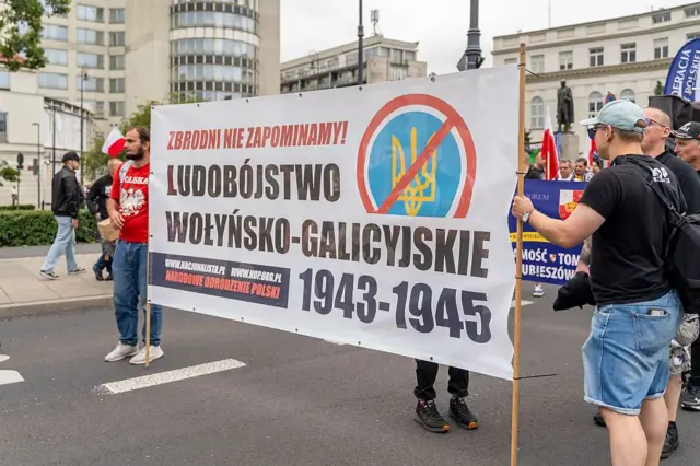 Протестувальники несуть банер з написом «Волинсько-галицький геноцид 1943-45» із зображенням перекресленого українського тризуба під час демонстрації у Варшаві, Польща, 12 липня 2026 року. (Фото Марека Антонія Іванчука/NurPhoto via Getty Images)