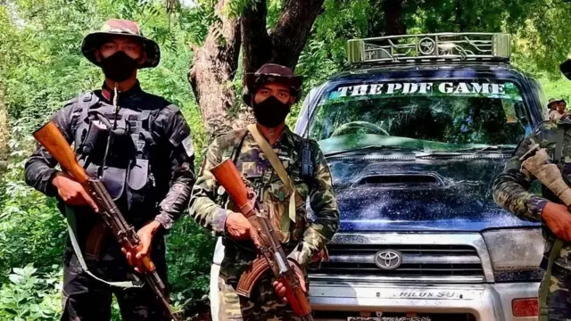 tentara PDF membawa senjata berpose di depan sebuah mobil