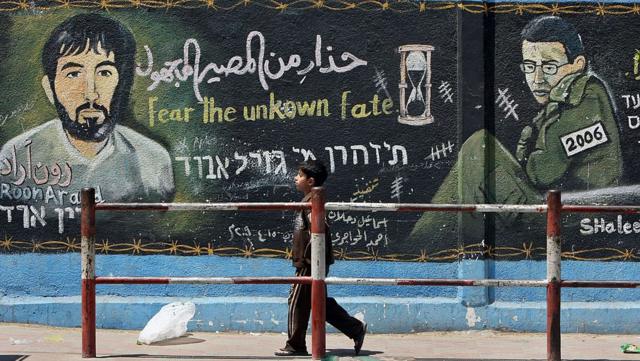 جدارية في مخيم جباليا في غزة عام 2010 يظهر فيها رون آراد إلى جانب الجندي  جلعاد شاليط الذي كان محتجزاً لدى حماس