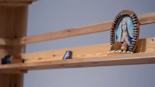 Une structure en bois avec divers objets sur les étagères, dont une image encadrée de la Vierge Marie.