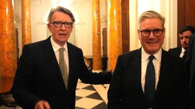 Takım elbiseli iki adam yan yana duruyor, kameraya gülümsüyorlar