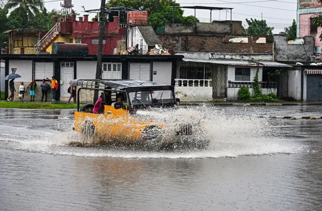 Un vehículo cruza una calle inundada en la ciudad de Santiago de Cuba.