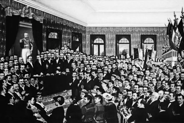 Foto em preto e branco de uma sala cheia de homens e mulheres