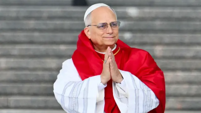 Pope Leo XIV wear white and red. E fold im hand dey look camera