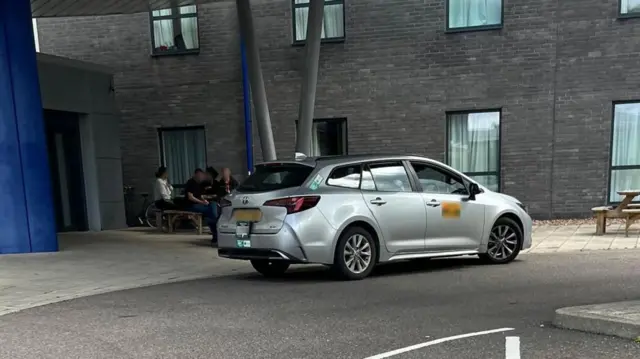Un taxi gris frente a un edificio sin identificar