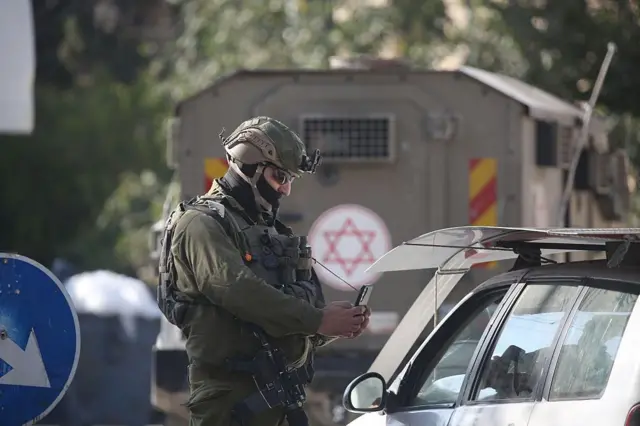 Un soldado le toma una foto a un conductor palestino en la ciudad de Nablusa, en Cisjordania
