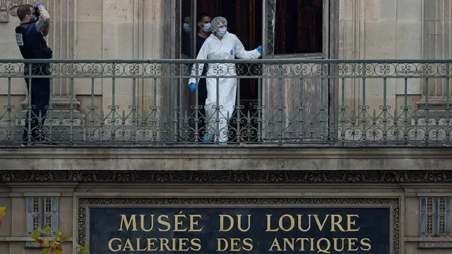 Louvre Müzesi'ne soyguncuların girdiği kapıda inceleme yapan polisler.