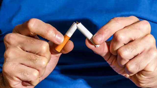 Homem partindo cigarro ao meio