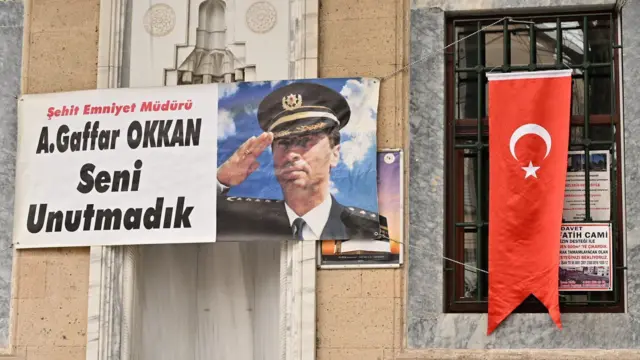 Gaffar Okkan'ın resminin olduğu bir pankart, 'Şehit Emniyet Müdürü A. Gaffar Okkan Seni Unutmadık' yazısıyla bir caminin duvarına asılmış