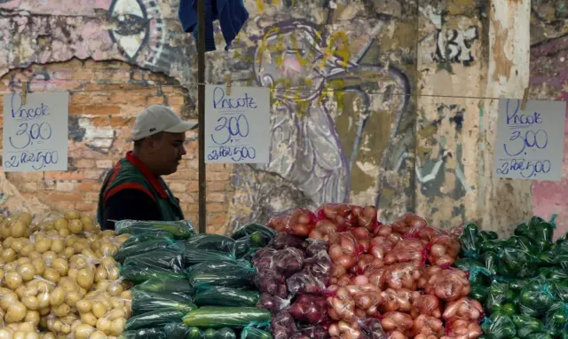 Feirante em frente a legumes expostos na sua barraca