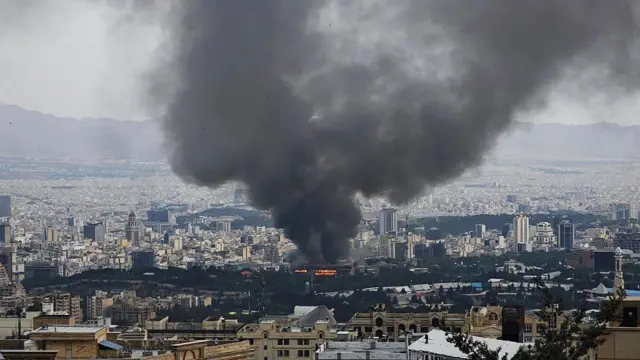 Asap mengepul setelah Israel dilaporkan menyerang sebuah gedung yang digunakan oleh media pemerintah Iran di Teheran, pada 16 Juni 2025.