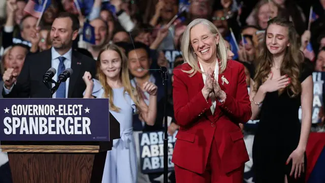 Кандидат в губернаторы от Демократической партии штата Вирджиния, бывший член Палаты представителей Абигейл Спанбергер празднует победу вместе со своей семьей. Абигейл (по середине) блондинка, в красном костюме, она улыбается и хлопает в ладоши. Позади нее плачет девушка в черном платье, слева девочка в голубом платье улыбается и поднимает руки вверх. Слева от нее улябается мужчина в синем костюме.