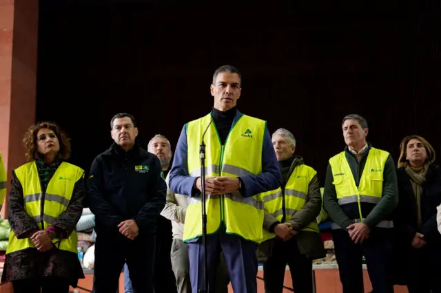 El presidente del gobierno de España, Pedro Sánchez, rodeado de otros funcionarios de Andalucía, todos con chalecos reflectantes, habla a la prensa sobre la tragedia