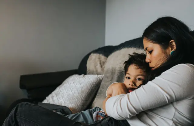 Mãe e filho abraçados no sofá