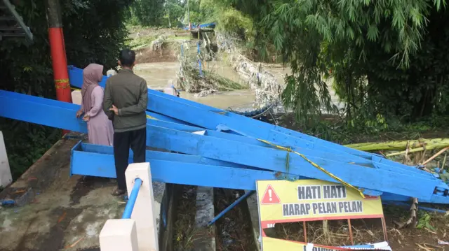 Warga mengamati jembatan gantung Darus atau Jembatan Cinta yang terputus akibat banjir di Desa Jubung, Sukorambi, Jember, Jawa Timur, Sabtu (14/2/2026).