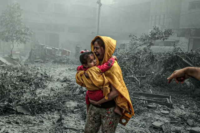 Hình ảnh một phụ nữ bế một bé gái trong một cuộc không kích của Israel nhằm vào Thành phố Gaza