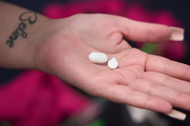 A patient holds two pills in her hand that she is taking as part of her surgical abortion procedure at a medical center in Phoenix, Arizona, USA on 12 April 2024.