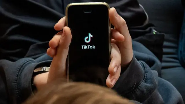 ilustrasinya, seorang anak laki-laki berusia 11 tahun sedang melihat aplikasi TikTok di layar smartphone.