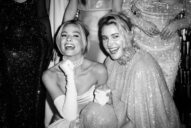 Margot Robbie e Greta Gerwig sorrindo e posando para foto com roupasluxo