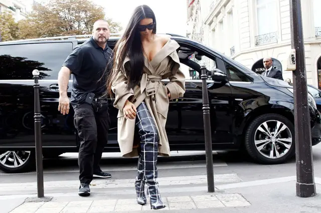 Кардашьян и телохранитель выходят из черной машины.