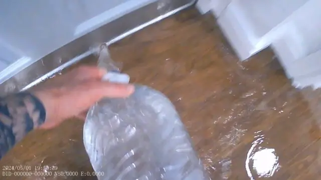 影片截圖顯示有人把一大瓶水倒進門下。
