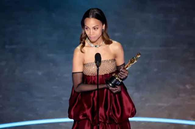 زوئی سالدانا مجمسمه طلایی را در دست گرفته است