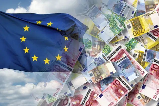 A kép bal oldalán az EU zászlója látható bárányfelhőkkel és kék éggel a háttérben, a jobb oldalon euró bankjegyek, 5, 10, 20, 50, 100 és 200 eurós címletek.
