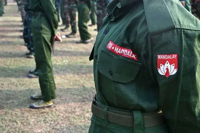 စစ်တပ်ရဲ့ မိဘထံပြန်အပ်နှံပွဲမှာ တွေ့ရတဲ့ MDY PDF အမှတ်တံဆိပ်ပါ ယူနီဖောင်းဝတ်ဆင်ထားတဲ့ အမျိုးသမီး