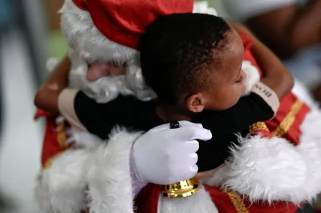 criança abraçando papai noel