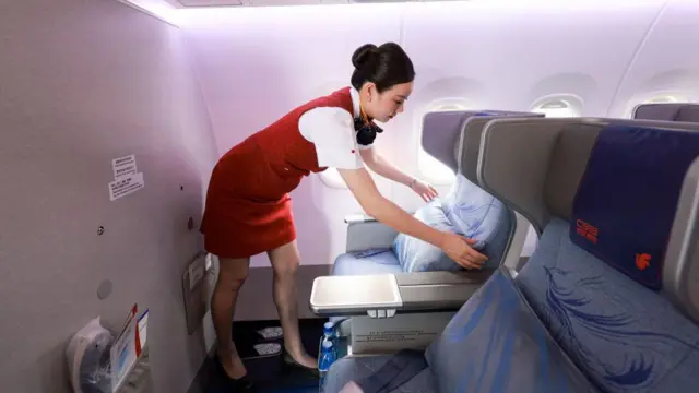 一名空中服務員正在機艙內整理座位。
