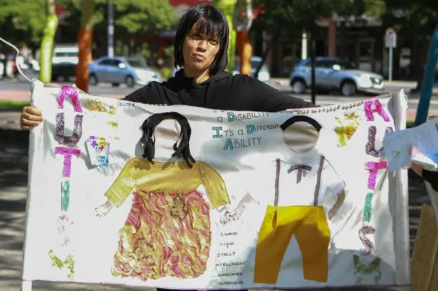 Une femme montrant une affiche sur laquelle sont dessinés deux enfants.