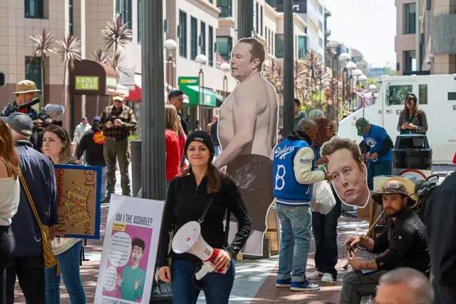 Протестувальники тримають вирізки з портретами Ілона Маска біля федеральної будівлі імені Рональда В. Деллумса та будівлі суду США під час початку судового розгляду справи Маск проти Альтмана в Окленді, Каліфорнія, 27 квітня 2026 року.