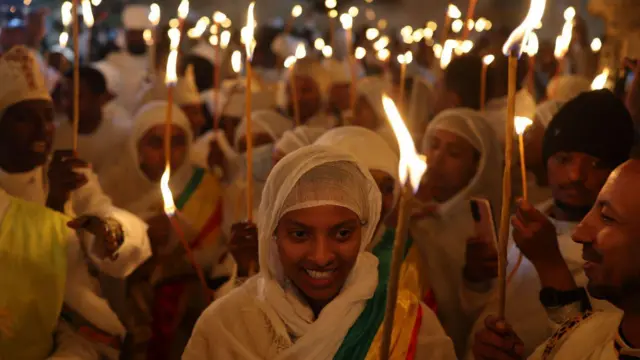 Desetine ljudi sa upaljenim svećama u rukama i odeveni u belo sa maramam preko glave