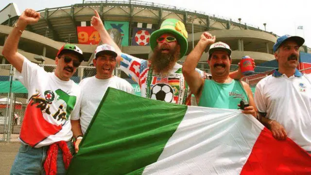 Torcedores italianos aguardam a chegada da sua seleção ao estádio, durante a Copa do Mundo de 1994, gritando e mostrando a bandeira do seu país