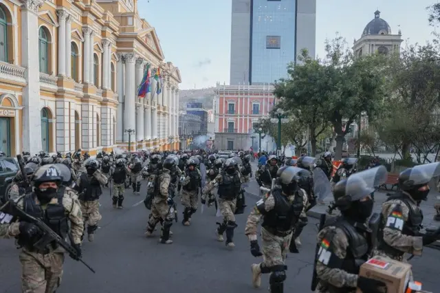 Dezenas de militares fortemente armados caminham em praça