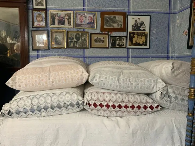 Šareni jastuci naređani na krevetu u sobi koja je okrečena u plavo