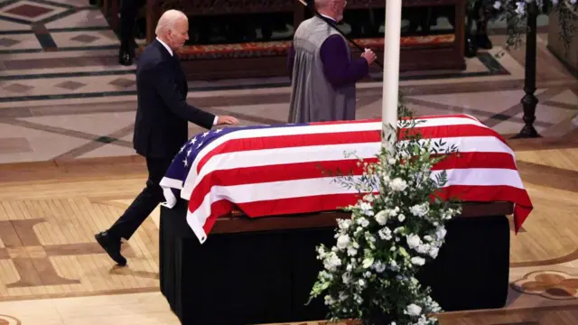 President Biden walking past the flag-draped casket of Jimmy Carter