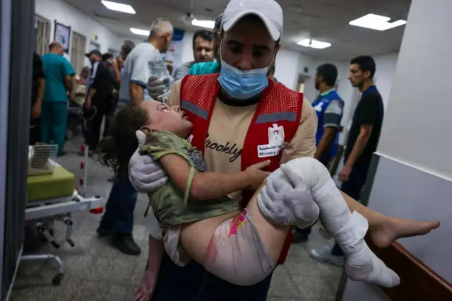 صورة أرشيفية لمسعف يحمل طفلة مجروحة ويدخل بها أحد المستشفيات لتلقي العلاج