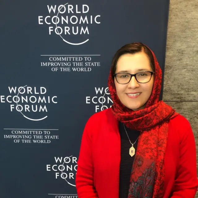 اورزلا نعمت، پژوهشگر و رئیس پیشین واحد تحقیق و ارزیابی افغانستان که چادر و جاکت سرخ و پیراهن سیاه دارد و در پشت سرش لوگوی فورم جهانی اقتصاد است.