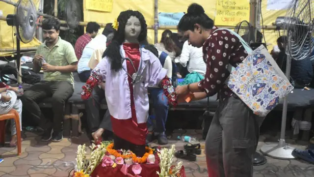 Seorang dokter di sebuah rumah sakit di Kolkata pada tanggal 19 Agustus mengikat Rakhis (benang suci tradisional India) di pergelangan tangan patung tanah liat yang menggambarkan dokter yang terbunuh