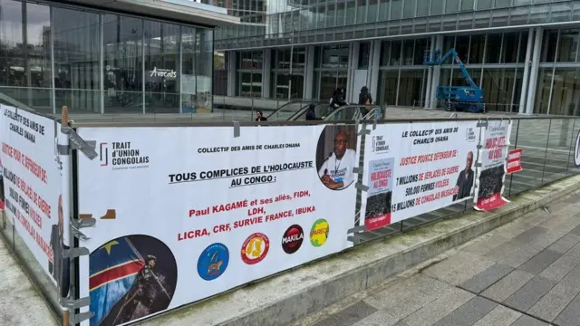 Icyapa kiri hanze y'urukiko i Paris mu Bufaransa, kiriho ifoto ya Charles Onana n'amagambo yo kumushyigikira yanditse mu Gifaransa, arimo n'ayo kwamagana Perezida w'u Rwanda Paul Kagame n'amashyirahamwe bivugwa ko bakorana. Ifoto yo ku itariki ya 9/12/2024