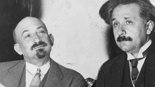 Dois homens de terno, lado a lado, observando em diferentes direções
