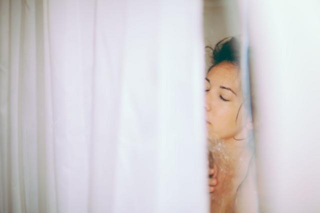 Mulher vista pela cortina tomando banho
