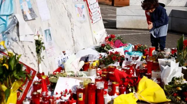 Uma criança perto da estátua do Papa João Paulo 2º no Hospital Gemelli, onde o Papa Francisco esteve internado para tratamento, em Roma, Itália