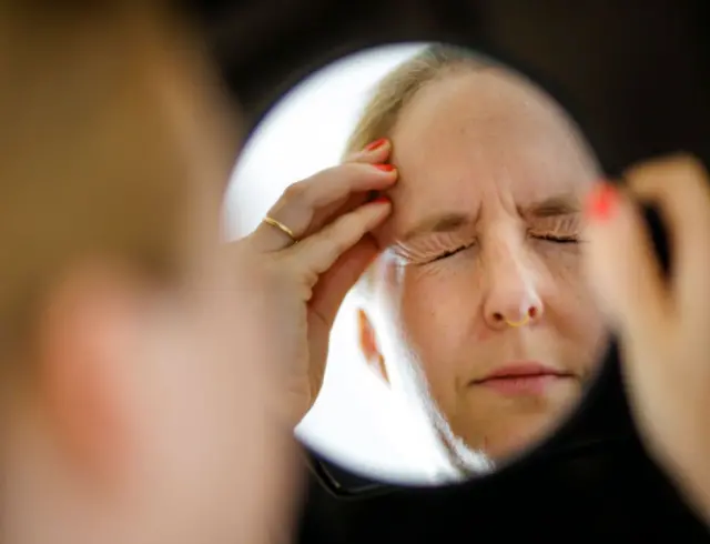 Символічне фото на тему мігрені та головного болю. Жінка тре рукою голову, яка болить