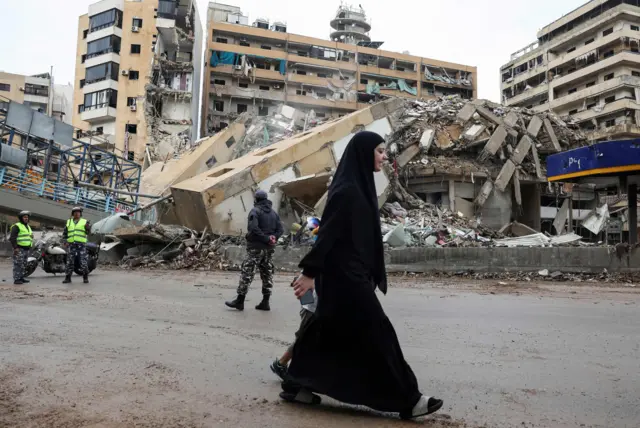 लेबननमा इजरेली आक्रमणका कारण भत्किएका भवनहरूको नजिकै रहेको बाटोमा हिँड्दै एक महिला